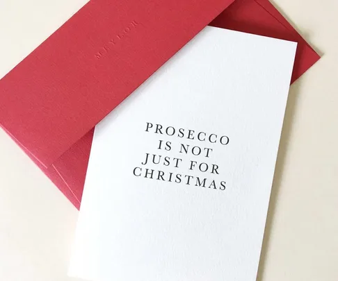 White card with "Prosecco is not just for Christmas" text, next to a red envelope.