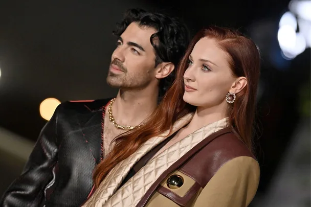 A couple poses stylishly at a nighttime event, wearing coordinated outfits with elegant accessories.