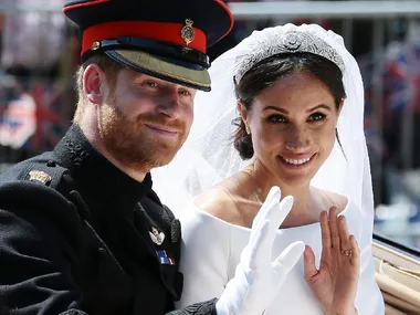 Prince Harry and Meghan Markle wave in wedding attire, smiling from a carriage.