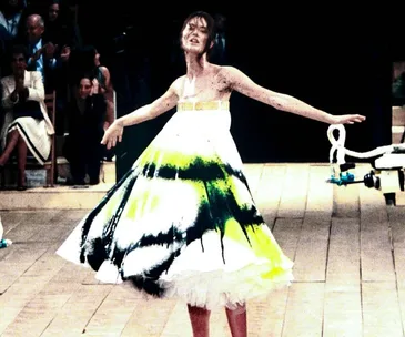 Model Shalom Harlow spins on the runway in a white dress being spray-painted during an Alexander McQueen fashion show.