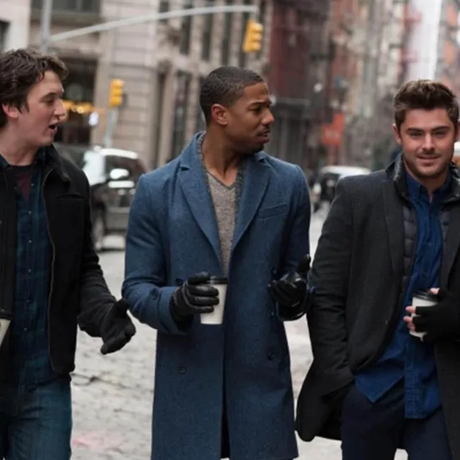 Three men walking on a city street, wearing coats and holding coffee cups, having a conversation.