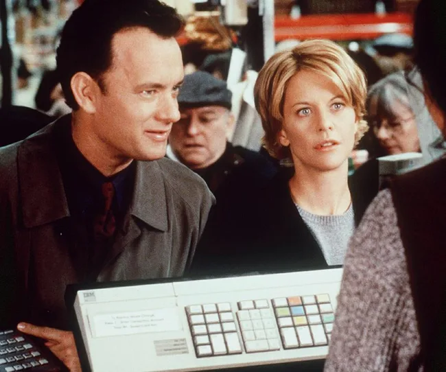 Two people stand at a checkout counter holding a keyboard, surrounded by a crowd.