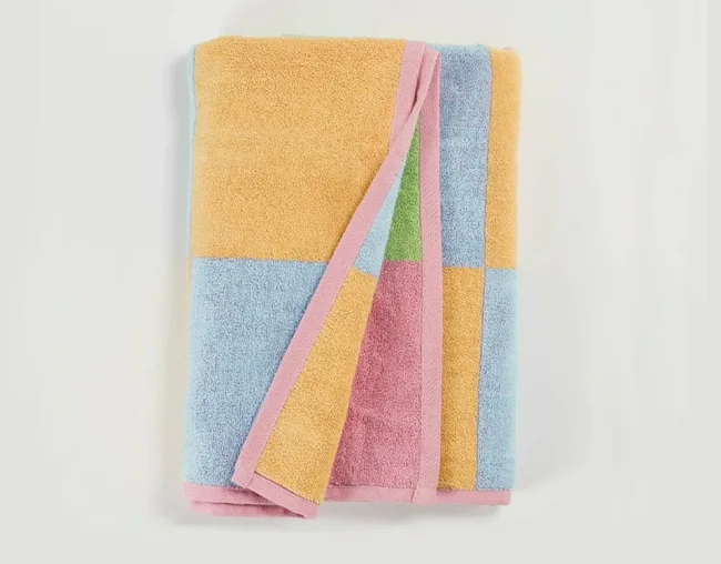 Folded towel with pastel blocks of yellow, blue, green, and pink on a light background.
