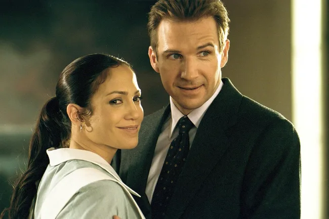 Two people are standing close, smiling, with one wearing a maid uniform and the other in a suit.