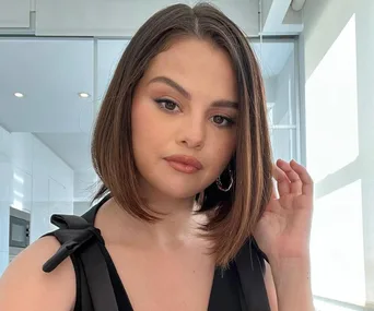 Woman with short brown hair poses indoors, wearing a black top.