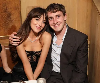 Two people sitting in a booth, smiling, with warm lighting and wood paneling in the background.