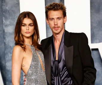 A couple poses together at the Oscars after-party, with one wearing a glittering dress and the other in a sleek suit.