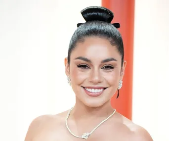 Vanessa Hudgens in Chanel jewelery at the 2023 Oscars, smiling with a sleek updo and radiant makeup.