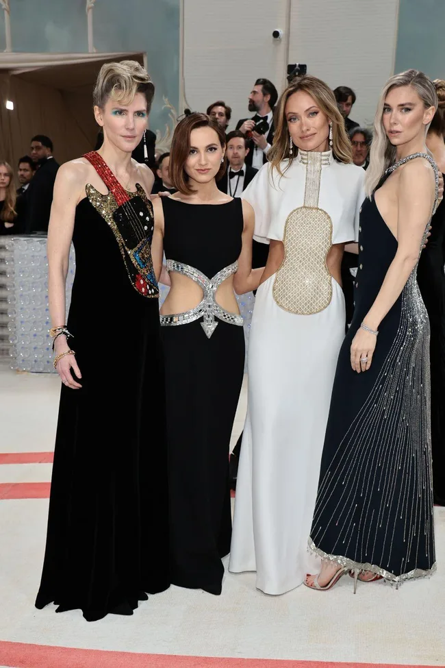 Four women pose in elegant gowns with cut-out designs at the Met Gala 2023 red carpet event.