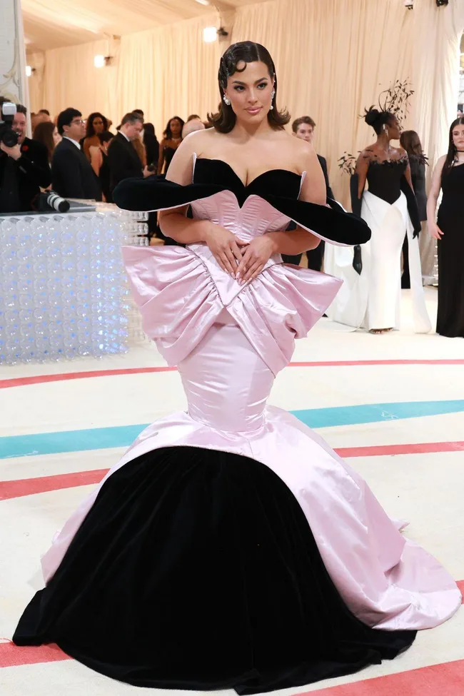 A person in a black and pink gown with structured design at the Met Gala 2023, elegant setting in the background.