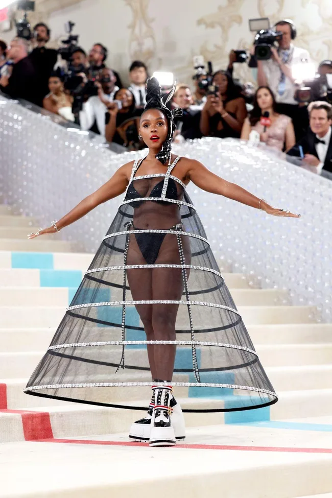 Singer in black cage dress at Met Gala 2023 with media capturing her.