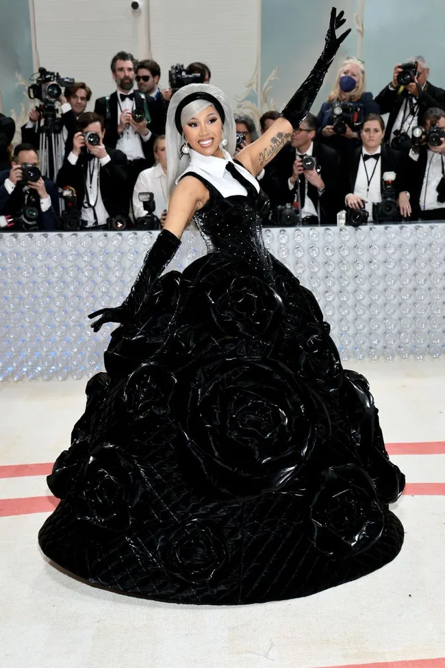 Person in a black and white gown with rose patterns, posing on the Met Gala 2023 red carpet.