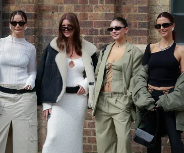 Four women in stylish outfits and sunglasses pose confidently at Australian Fashion Week 2023.