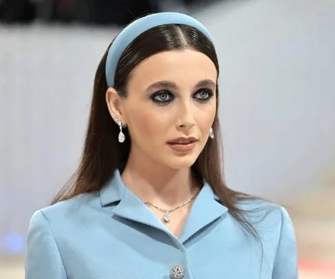 Woman at 2023 Met Gala in a light blue outfit and headband, with striking eye makeup and elegant jewelry.