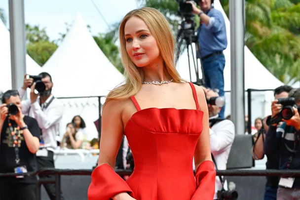 Actress in a stunning red gown on the Cannes 2023 red carpet, posing for photographers.