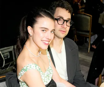 A woman in a floral dress and a man in glasses smiling at an event.