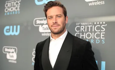 Man in tuxedo at 23rd Critics' Choice Awards with logo backdrop.