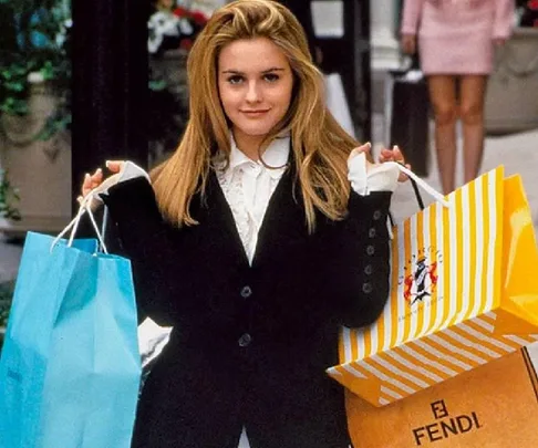 Young woman holding colorful shopping bags, smiling outdoors.