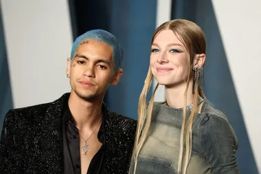 Two people at a glamorous event, one with blue hair, both dressed in stylish attire.