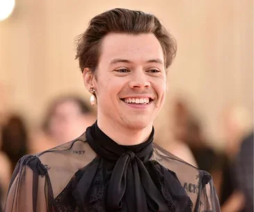 Person wearing a sheer black top with a big smile, in a formal event setting.