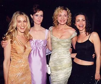 Four women posing together at an event, dressed in elegant evening gowns.