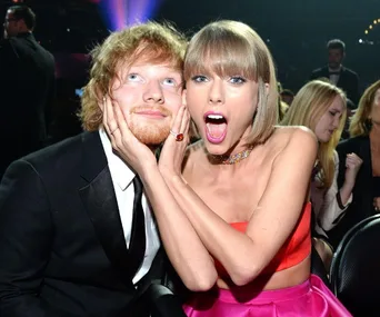 Two excited people posing together at an event, the woman has her hands on the man's face, both smiling.