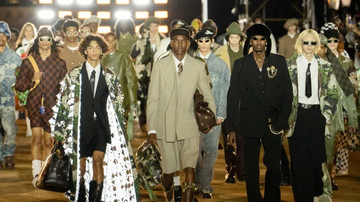 Models walking in a Louis Vuitton fashion show, wearing a variety of stylish, eclectic outfits and accessories.