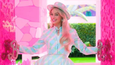 A woman in pastel clothes opens a pink door with large keys in a vibrant, colorful setting.