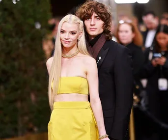 A couple in formal attire posing at an event; the woman in a yellow dress, the man in a dark suit.