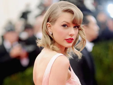 Woman in a pink dress with red lipstick and short blonde hair at a formal event.