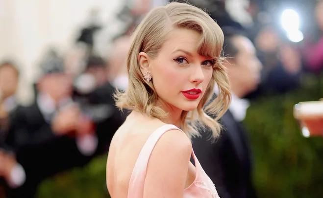 Woman in a pink dress with red lipstick and short blonde hair at a formal event.