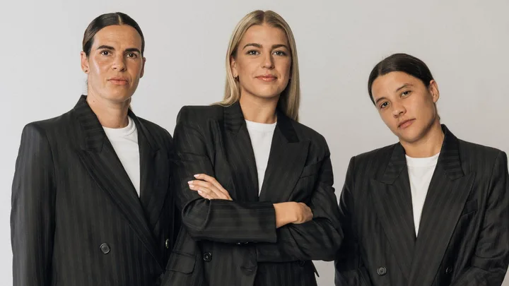 Three individuals in matching pinstripe blazers and white shirts against a plain background.