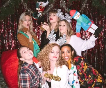 Group of women in festive attire and antlers posing at a Christmas party.