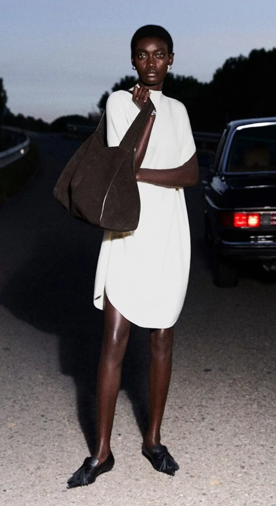 Model wears a white dress with brown and black accessories