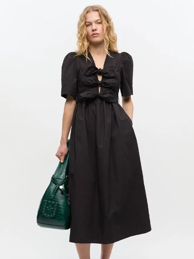 Model wearing a black midi dress from Ganni