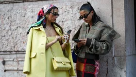 Two women holding phones at fashion week.