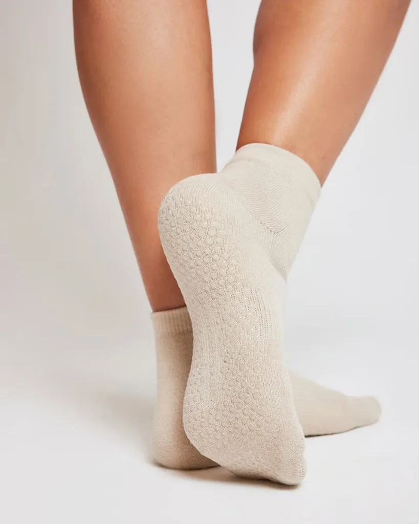 a model's legs from the calf down wearing a pair of oatmeal-coloured pilates grip socks