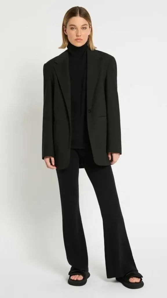 Soft black cashmere pant from Sass and Bide with a high waist. The pant hugs the leg before flaring out and is here styled with black sandals and a black blazer. 