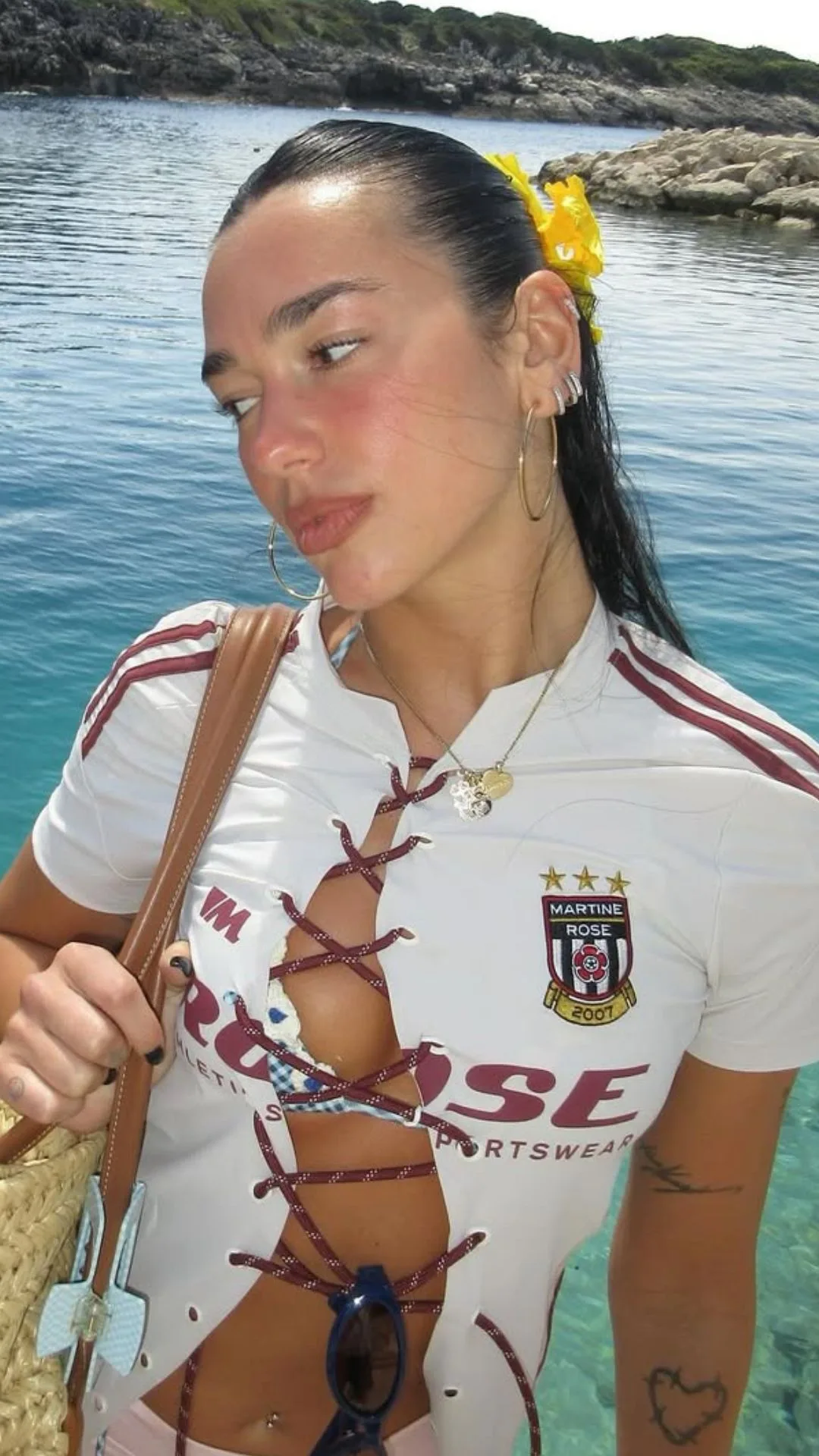 Dua Lipa with a flower in her hair by the sea 