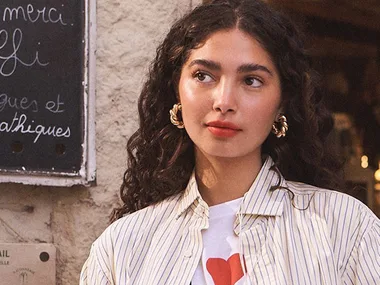 Woman with gold hoop earrings and dark brown, curly hair