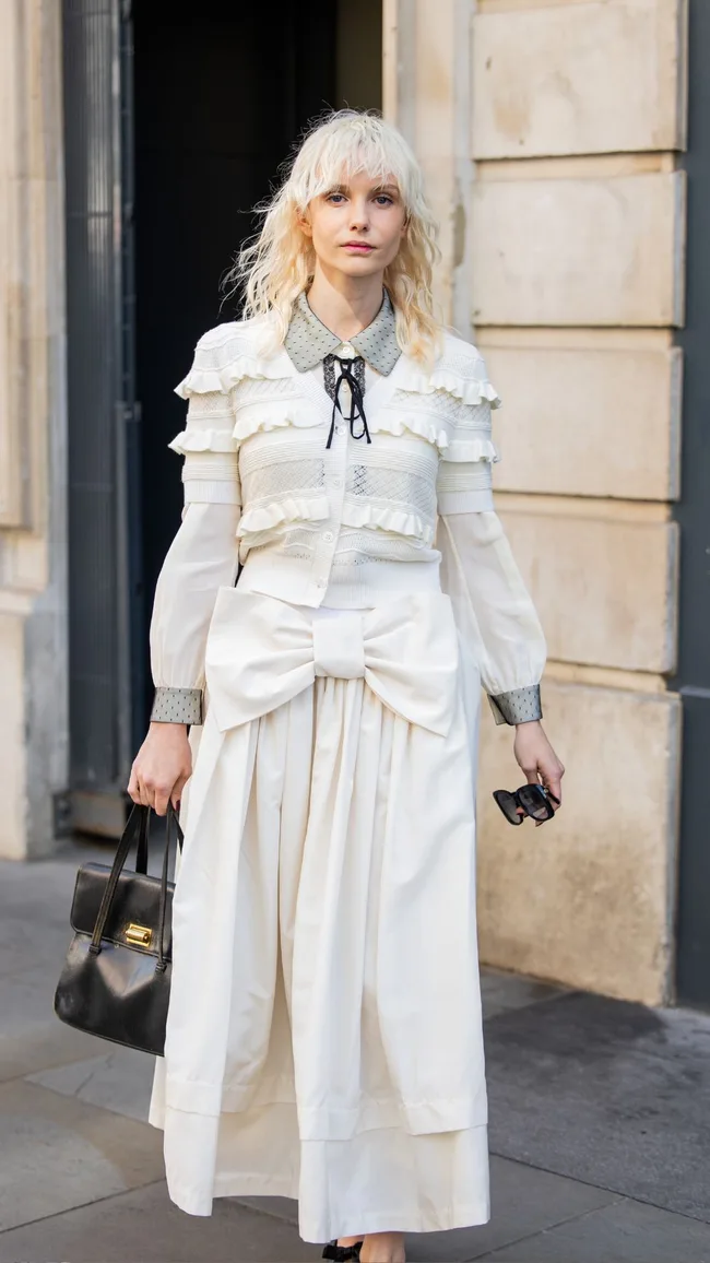 A guest wears white ruffled top, black bag outside Bora Aksu during London Fashion Week September 2024 on September 13, 2024 in London, England.