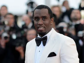 diddy sean combs wearing a white suit and black tie