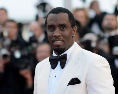 diddy sean combs wearing a white suit and black tie