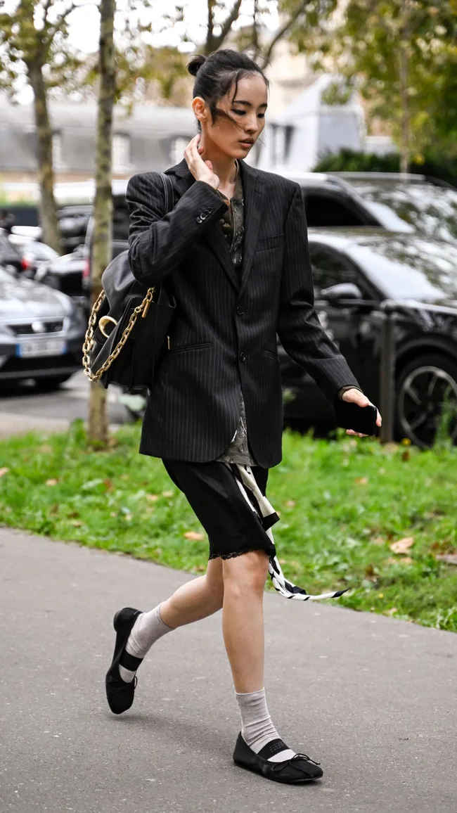 a street style photo of a woman wearing shorts and flats at paris fashion week