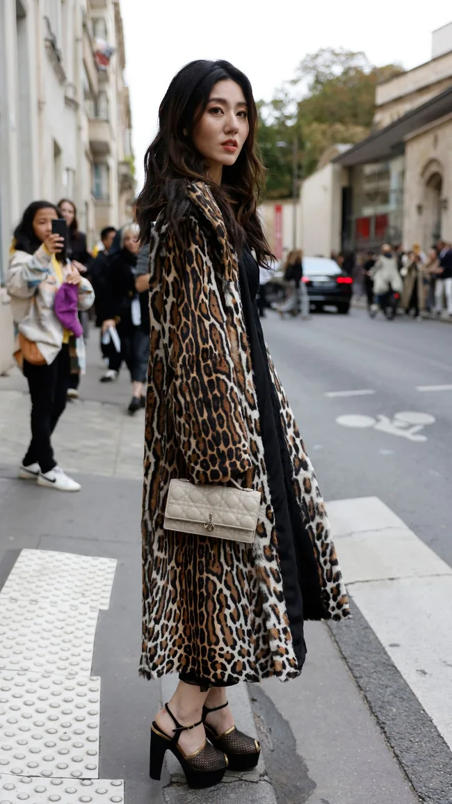 a woman in a leopard print coat at paris fashion week