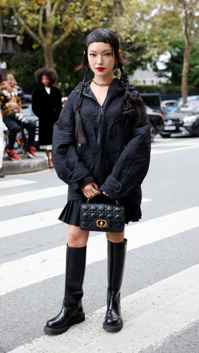 a woman wears long black boots at paris fashion week