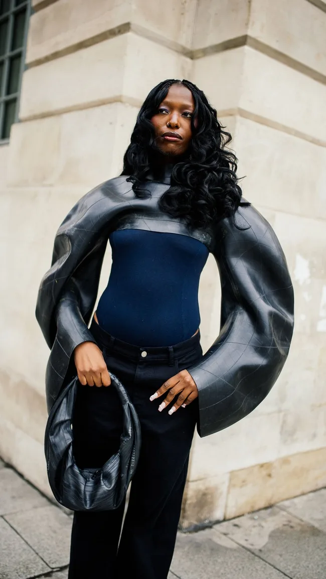 a woman wears a sculptural top with curved sleeves at paris fashion week