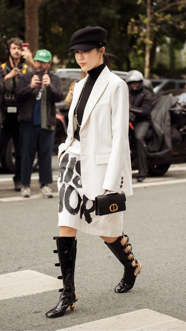 a woman at paris fashion week wearing a white skirt with black miss dior text