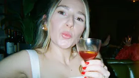 Woman looking at the camera, holding a cocktail.