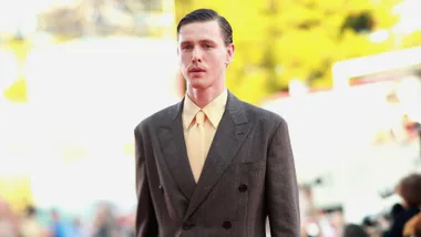 harris dickinson wears a suit with yellow shirt